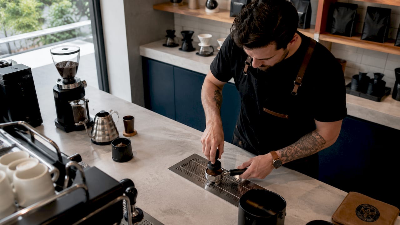 Barista tamping espresso grounds close-up