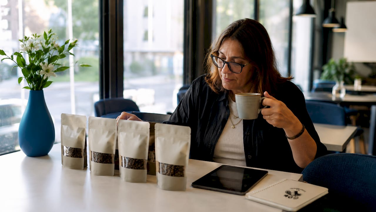 Woman reviewing four coffee subscription bags at kitchen table