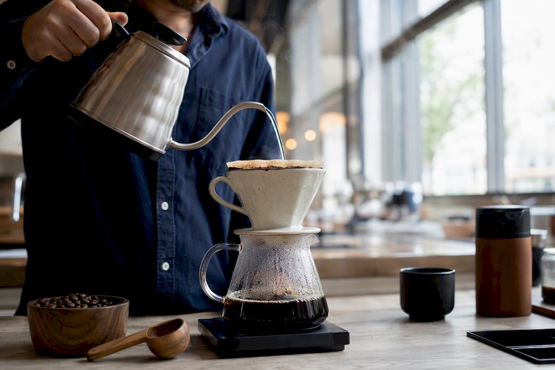 Hands pouring water over coffee grounds in dripper