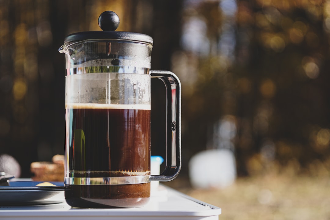 Hands pouring water into French press over coffee grounds