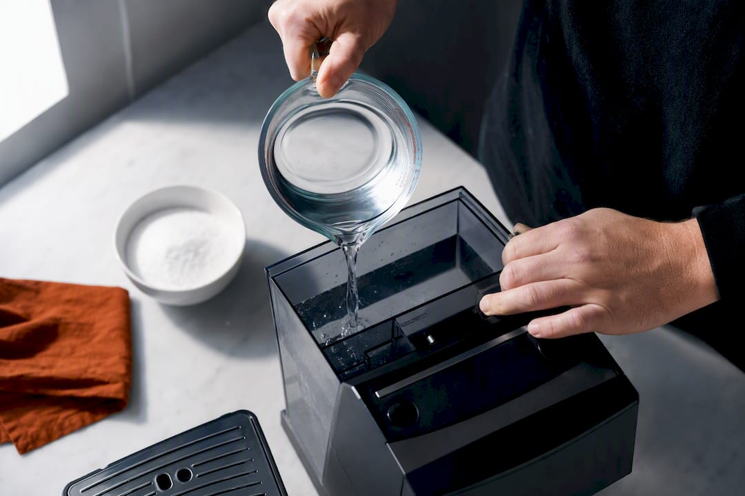 Hands preparing citric acid coffee machine descaler