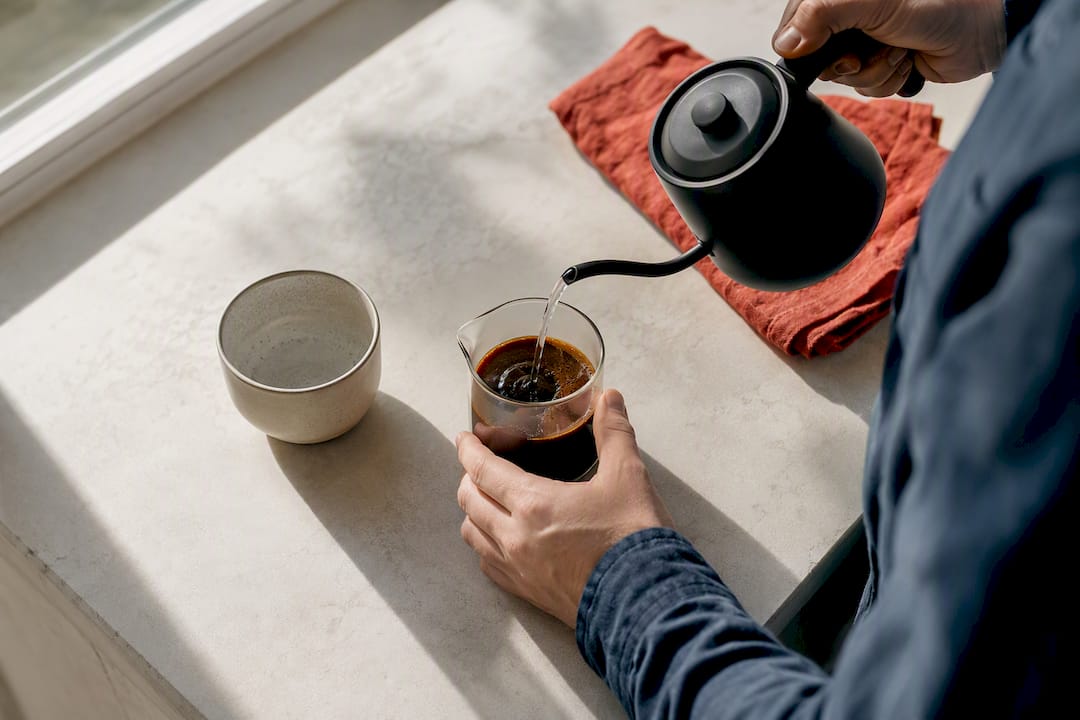 Hands diluting concentrated coffee into Americano