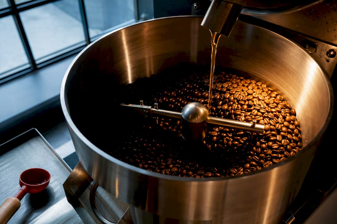 Warm coffee beans being coated with flavor oil